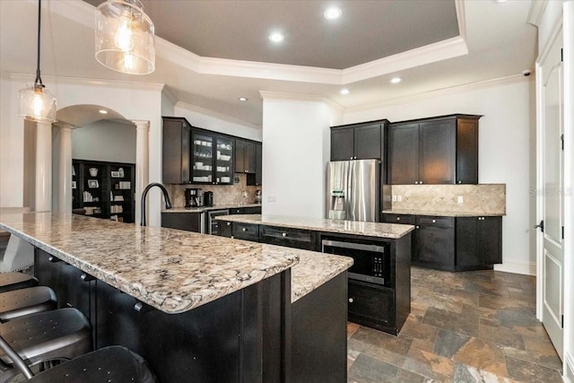 6357 Ashley Dr, Lakeland, FL 33813 - kitchen with ornate columns, stainless steel appliances, a kitchen island, backsplash, and ornamental molding