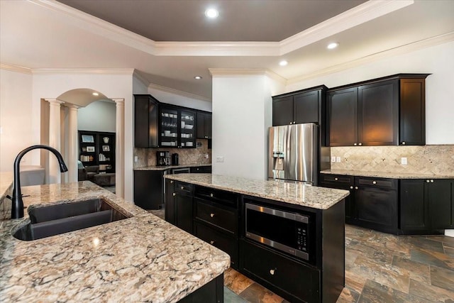 6357 Ashley Dr, Lakeland, FL 33813 - kitchen with appliances with stainless steel finishes, decorative columns, a sink, a kitchen island, and dark cabinetry