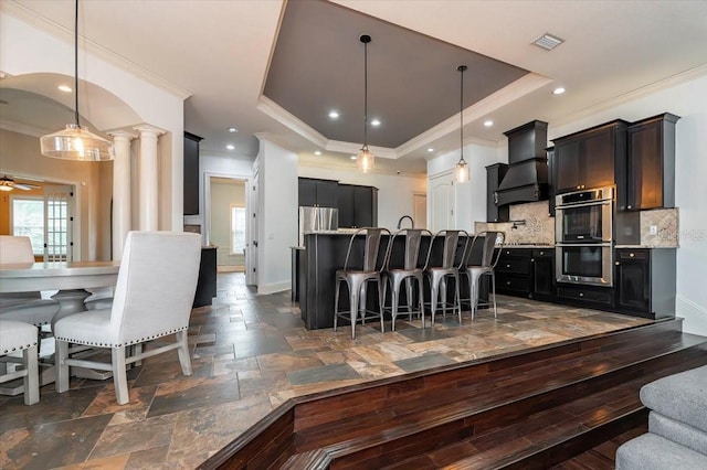 6357 Ashley Dr, Lakeland, FL 33813 - kitchen featuring ornamental molding, stainless steel appliances, custom range hood, a breakfast bar area, and backsplash