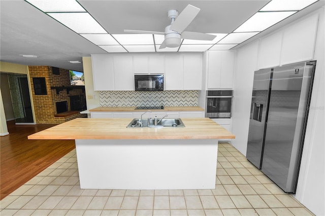 5425 Lewellyn Rd, Lakeland, FL 33810 - kitchen featuring black appliances, a sink, butcher block counters, a ceiling fan, and a brick fireplace