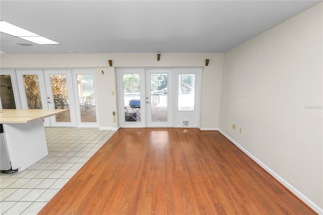 5425 Lewellyn Rd, Lakeland, FL 33810 - unfurnished living room with french doors, baseboards, a skylight, and light wood-style flooring