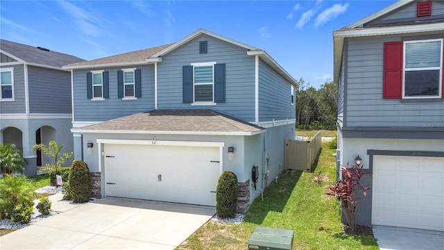 traditional-style home with a shingled roof, an attached garage, and concrete driveway