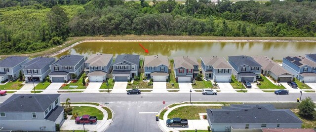 aerial perspective of suburban area with a nearby body of water and a forest