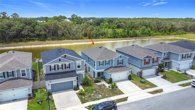 aerial perspective of suburban area featuring a forest and a nearby body of water