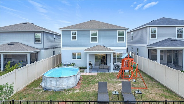 back of property with a playground, a patio, a sunroom, and roof with shingles