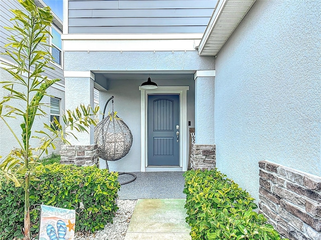 doorway to property featuring stucco siding and stone siding