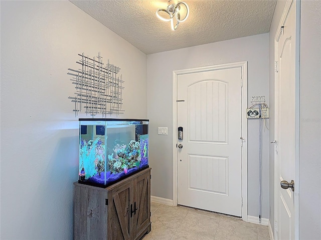 foyer featuring a textured ceiling, light tile patterned floors, and baseboards