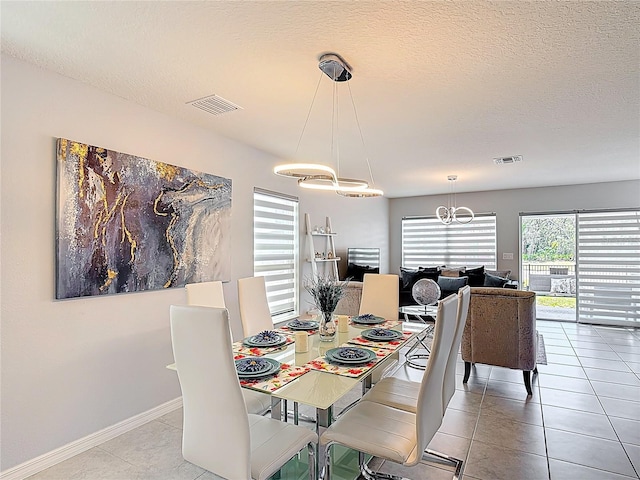 dining area with a chandelier, tile patterned floors, a textured ceiling, and baseboards