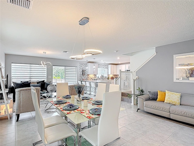 dining space with a chandelier, light tile patterned floors, and a textured ceiling
