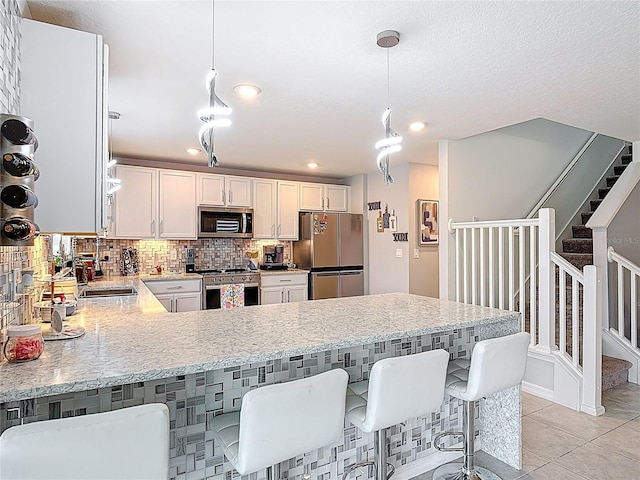 kitchen with stainless steel appliances, a peninsula, a sink, tasteful backsplash, and white cabinetry