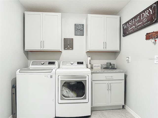 laundry area featuring independent washer and dryer, cabinet space, baseboards, a textured ceiling, and light tile patterned flooring