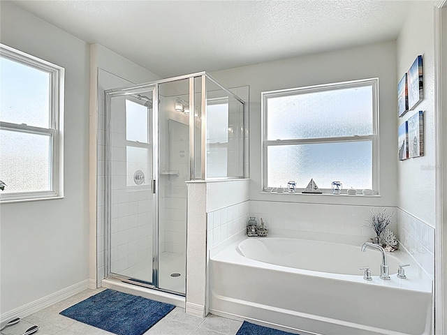 full bathroom featuring plenty of natural light, a stall shower, a garden tub, tile patterned flooring, and a textured ceiling