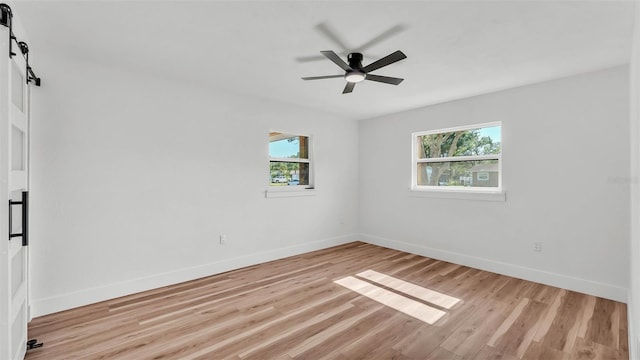 6543 Tula Ln, Lakeland, FL 33809 - spare room featuring plenty of natural light, light wood-style flooring, a barn door, and baseboards