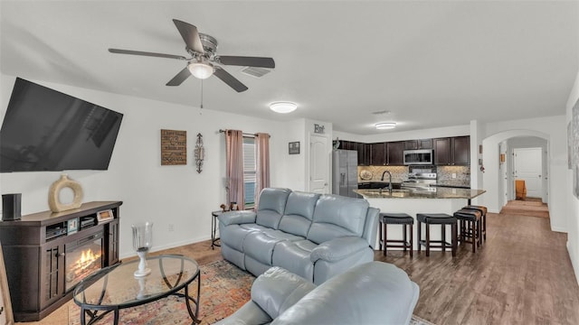 2293 Caspian Dr, Lakeland, FL 33805 - living room with a ceiling fan, arched walkways, a glass covered fireplace, baseboards, and wood finished floors