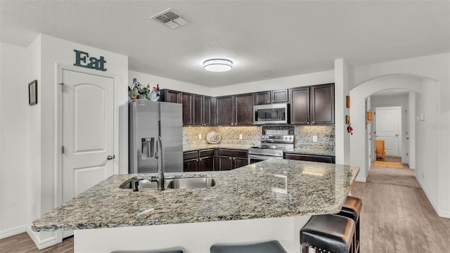 2293 Caspian Dr, Lakeland, FL 33805 - kitchen featuring appliances with stainless steel finishes, a sink, arched walkways, a breakfast bar, and a textured ceiling