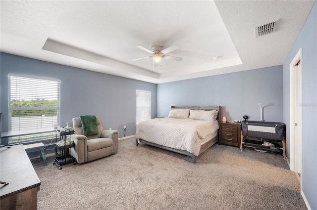 3883 Sandhill Crane Dr, Lakeland, FL 33811 - carpeted bedroom featuring a tray ceiling, multiple windows, ceiling fan, and baseboards