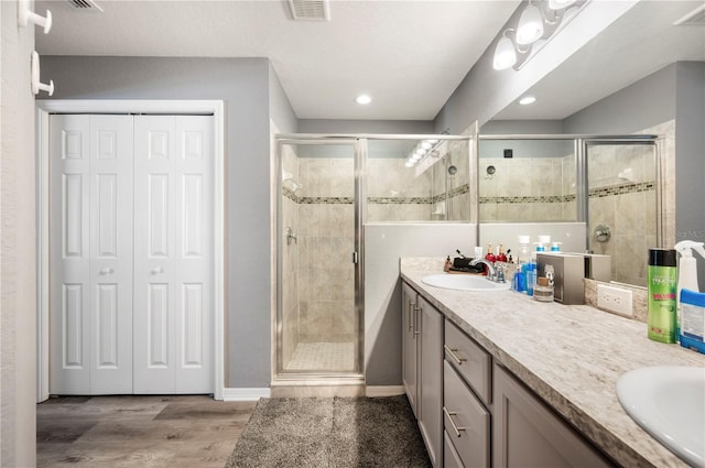 3883 Sandhill Crane Dr, Lakeland, FL 33811 - bathroom with double vanity, a shower stall, a closet, wood finished floors, and recessed lighting