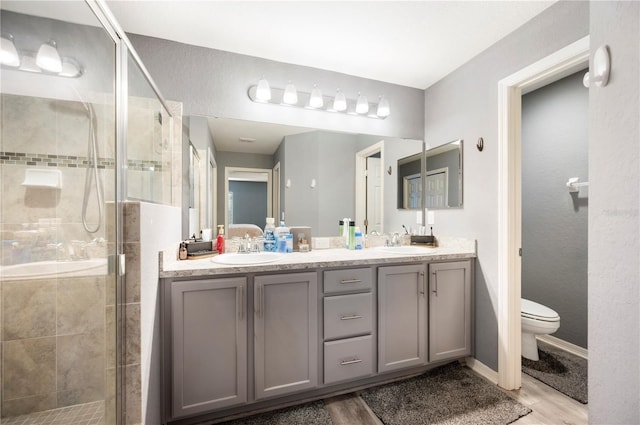 3883 Sandhill Crane Dr, Lakeland, FL 33811 - full bath with double vanity, toilet, wood finished floors, a shower stall, and baseboards