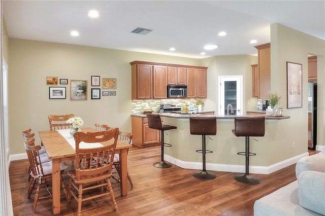 1233 Emerald Hill Way, Valrico, FL 33594 - kitchen with appliances with stainless steel finishes, a kitchen breakfast bar, a peninsula, backsplash, and light wood finished floors