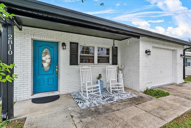 2810 Gary Ln, Lakeland, FL 33812 - doorway to property with brick siding, a porch, a garage, and concrete driveway