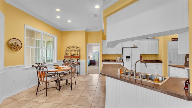 2025 Viewpoint Landings Rd, Lakeland, FL 33810 - kitchen featuring white fridge with ice dispenser, a sink, dark countertops, crown molding, and wainscoting