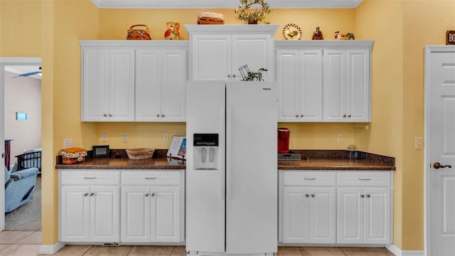 2025 Viewpoint Landings Rd, Lakeland, FL 33810 - kitchen featuring white refrigerator with ice dispenser, white cabinets, light tile patterned flooring, ornamental molding, and dark stone counters