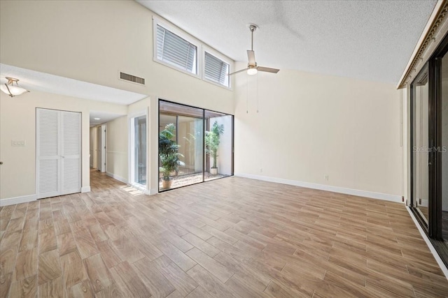 107 Seville Ct N, Plant City, FL 33566 - unfurnished living room featuring baseboards, light wood-style floors, a textured ceiling, a ceiling fan, and high vaulted ceiling
