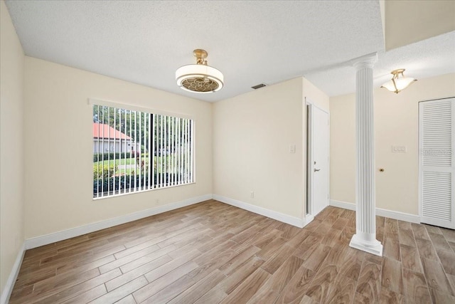 107 Seville Ct N, Plant City, FL 33566 - spare room featuring decorative columns, wood finished floors, a textured ceiling, and baseboards