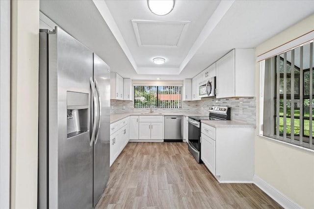 107 Seville Ct N, Plant City, FL 33566 - kitchen featuring appliances with stainless steel finishes, light countertops, tasteful backsplash, white cabinets, and light wood finished floors