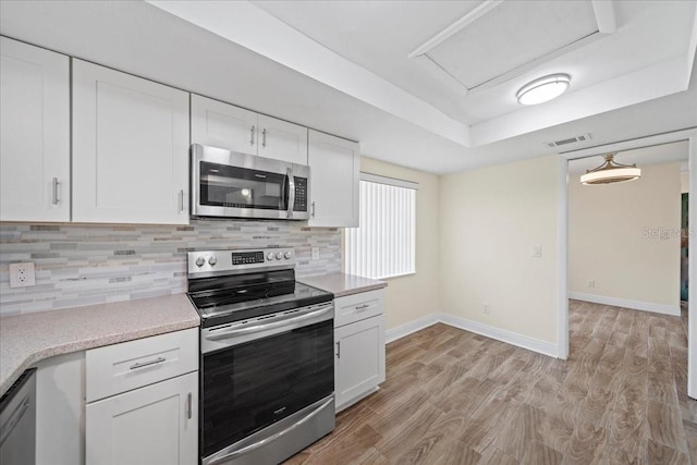 107 Seville Ct N, Plant City, FL 33566 - kitchen featuring stainless steel appliances, a raised ceiling, white cabinetry, and light countertops