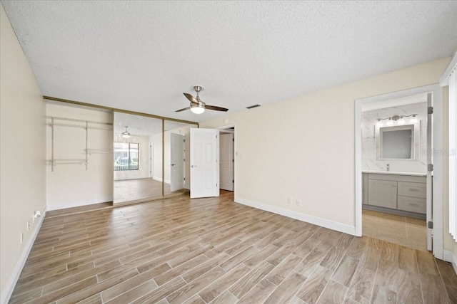 107 Seville Ct N, Plant City, FL 33566 - unfurnished bedroom featuring light wood-style floors, a textured ceiling, baseboards, ensuite bathroom, and a ceiling fan