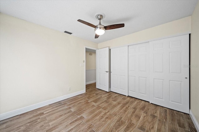 107 Seville Ct N, Plant City, FL 33566 - unfurnished bedroom with light wood-style floors, baseboards, a closet, a ceiling fan, and a textured ceiling