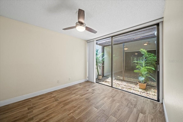 107 Seville Ct N, Plant City, FL 33566 - empty room with wood finished floors, a textured ceiling, baseboards, a ceiling fan, and expansive windows