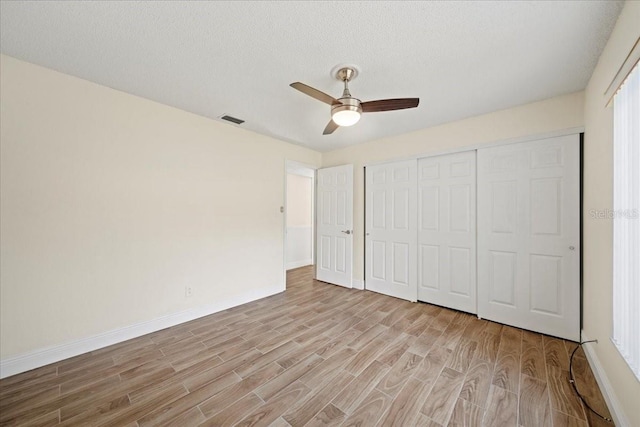 107 Seville Ct N, Plant City, FL 33566 - unfurnished bedroom featuring light wood-style floors, baseboards, a closet, ceiling fan, and a textured ceiling