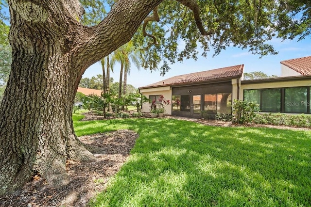 107 Seville Ct N, Plant City, FL 33566 - rear view of property featuring a yard, a tile roof, stucco siding, and a sunroom