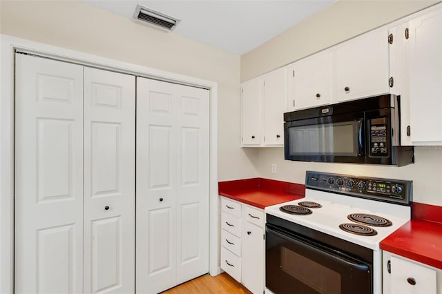 3427 S Polk Ave, Lakeland, FL 33803 - kitchen with black microwave, range with electric stovetop, white cabinets, and light wood-style floors