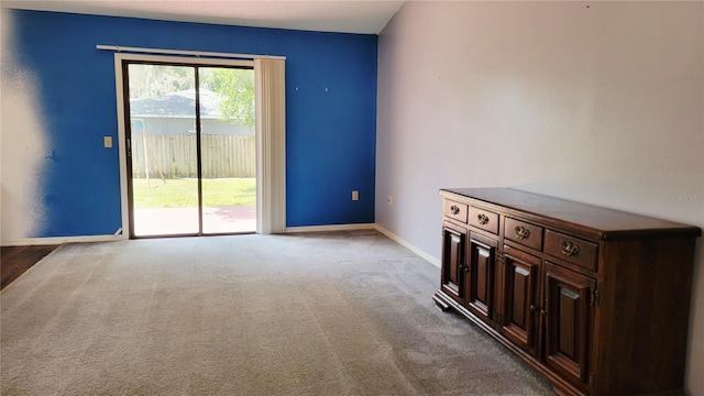 unfurnished living room with baseboards and carpet