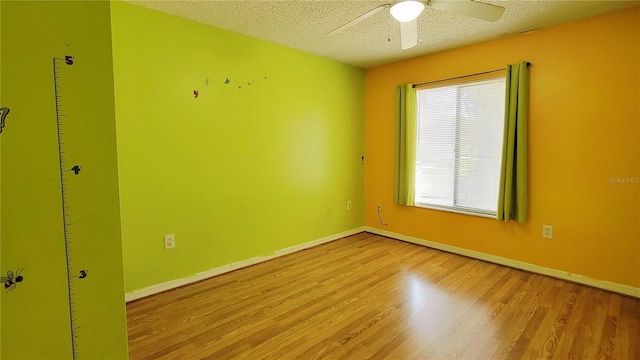 empty room featuring light wood-style flooring, ceiling fan, a textured ceiling, and baseboards