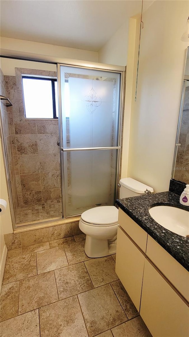 full bath featuring a shower stall, vanity, toilet, and stone tile flooring