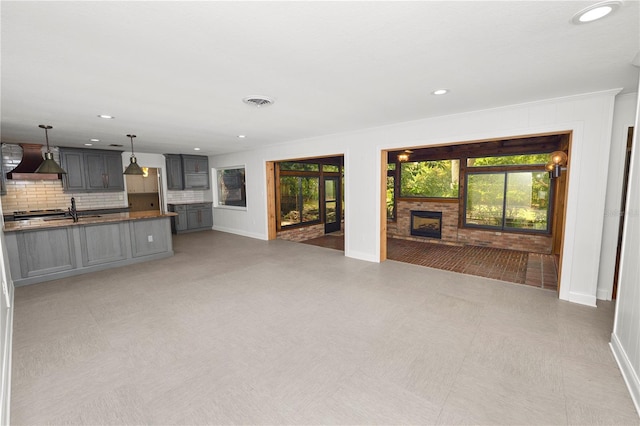 509 Rob Roy St, Lakeland, FL 33813 - unfurnished living room featuring a fireplace with raised hearth, baseboards, recessed lighting, a sink, and light flooring