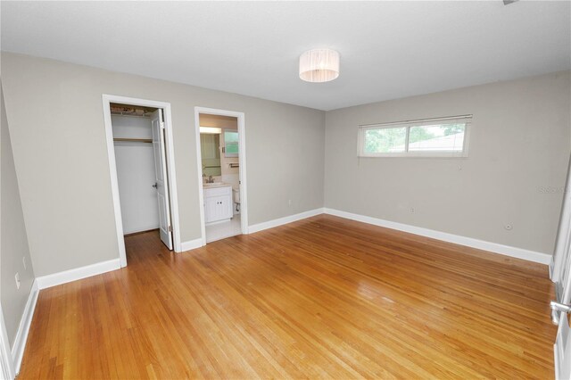 509 Rob Roy St, Lakeland, FL 33813 - unfurnished bedroom featuring a spacious closet, baseboards, a closet, light wood finished floors, and connected bathroom
