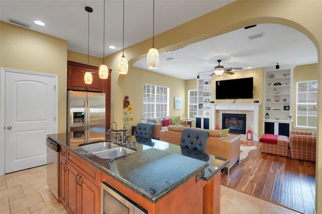 2731 Coventry Ave, Lakeland, FL 33803 - kitchen featuring appliances with stainless steel finishes, a sink, arched walkways, dark stone counters, and brown cabinetry