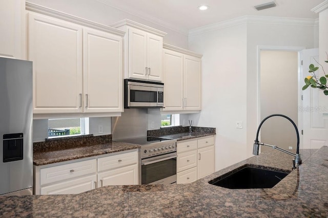 2425 Laurel Glen Dr, Lakeland, FL 33803 - kitchen featuring stainless steel appliances, white cabinets, dark stone counters, ornamental molding, and recessed lighting