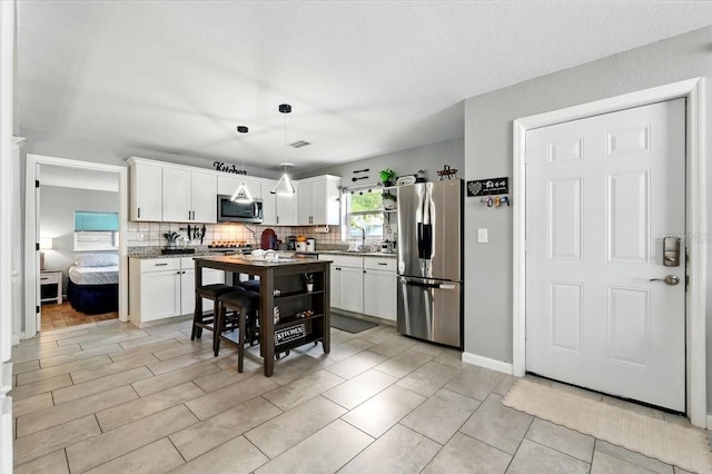1648 Skinner St, Lakeland, FL 33801 - kitchen with appliances with stainless steel finishes, decorative backsplash, white cabinets, and pendant lighting