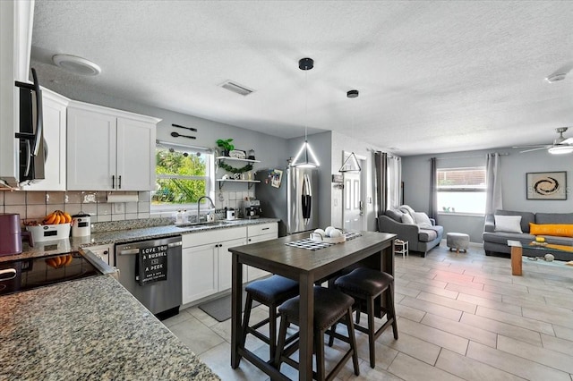 1648 Skinner St, Lakeland, FL 33801 - kitchen featuring appliances with stainless steel finishes, a sink, open floor plan, a textured ceiling, and healthy amount of natural light