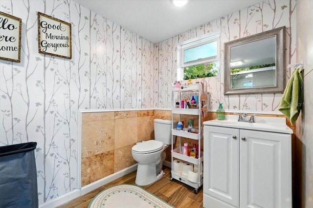 1648 Skinner St, Lakeland, FL 33801 - half bathroom featuring wallpapered walls, toilet, wainscoting, wood finished floors, and vanity