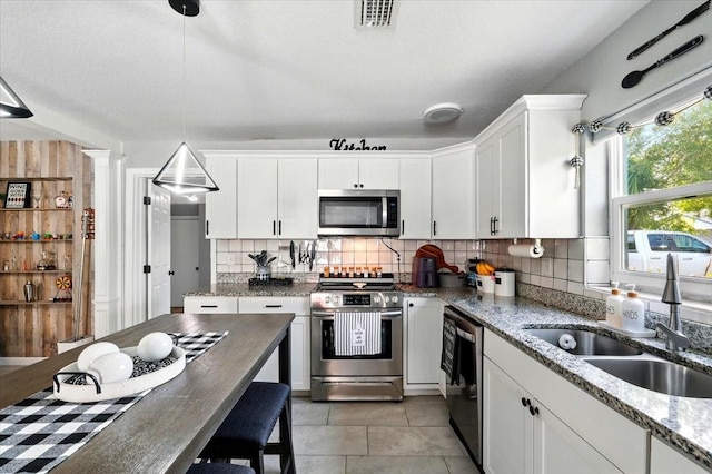1648 Skinner St, Lakeland, FL 33801 - kitchen featuring appliances with stainless steel finishes, a sink, tasteful backsplash, white cabinetry, and pendant lighting