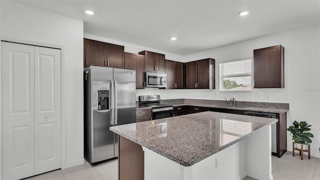 2546 Red Egret Dr, Bartow, FL 33830 - kitchen with appliances with stainless steel finishes, a sink, light stone counters, dark brown cabinetry, and a kitchen island