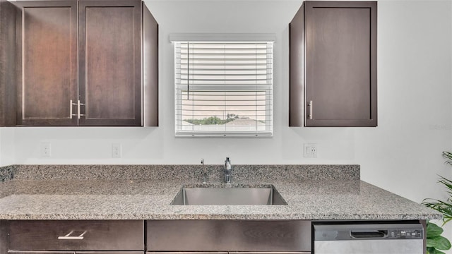 2546 Red Egret Dr, Bartow, FL 33830 - kitchen with stainless steel dishwasher, a sink, dark brown cabinetry, and light stone countertops