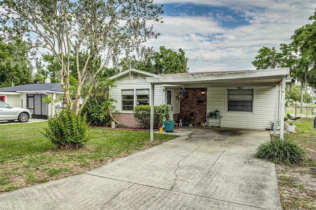 102 Pike St, Auburndale, FL 33823 - view of front of house featuring a front lawn, concrete driveway, a carport, and brick siding